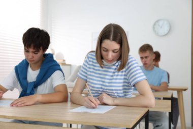 Ahşap masada sınava giren öğrenciler