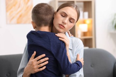 Anne, üzgün oğlunu evde destekleyip kucaklıyor.