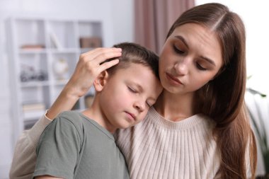 Anne, üzgün oğlunu evde destekleyip kucaklıyor.