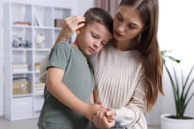 Anne, üzgün oğlunu evde destekleyip kucaklıyor.