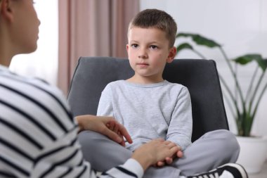 Anne üzgün oğlunu evde destekliyor, yakın plan.