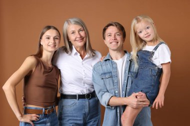 Kahverengi arka planda oğlu ve ailesi olan yaşlı bir kadının portresi.