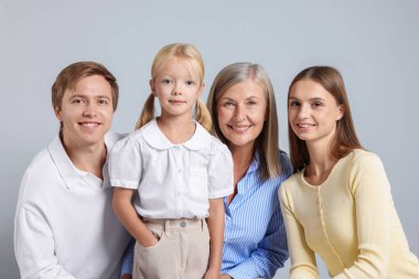 Aydınlık bir arkaplanda oğlu ve ailesi olan yaşlı bir kadının portresi.