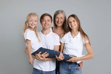 Açık gri arka planda oğlu ve ailesiyle birlikte son sınıf öğrencisi bir kadının portresi.