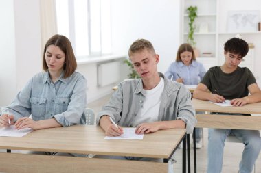 Ahşap masada sınava giren öğrenciler