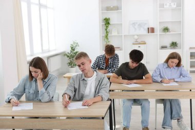 Ahşap masada sınava giren öğrenciler