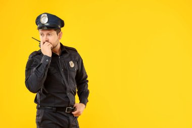 Sarı arka planda telsizi olan üniformalı bir polis memuru. Mesaj için yer var.