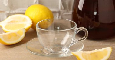 Ahşap masada cam fincana aromatik çay dökerek.