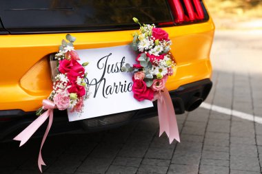 Düğün arabası. Cabriolet dekore edilmiş. Sadece evlilik kartı ve açık havada güzel çiçekler, yakın plan.