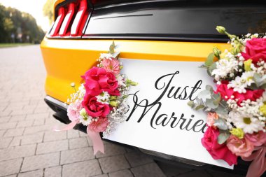 Düğün arabası. Cabriolet dekore edilmiş. Sadece evlilik kartı ve açık havada güzel çiçekler, yakın plan.