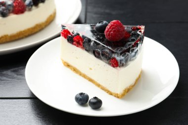 Piece of delicious cheesecake with berries on black wooden table, closeup