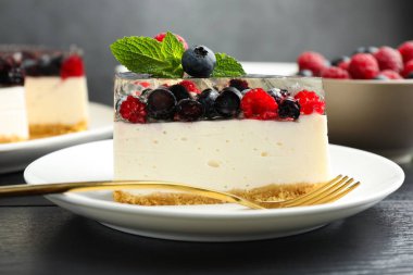 Lezzetli peynirli kek, böğürtlenli ve nane şekerli, siyah ahşap masa, yakın plan.