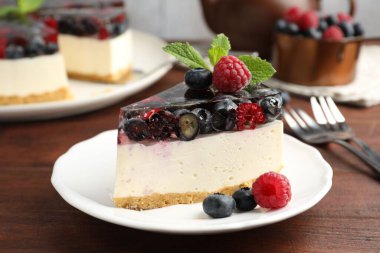 Bir parça lezzetli peynirli kek, böğürtlenli ve nane şekerli, ahşap masada servis ediliyor, yakın plan.