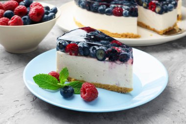 Piece of delicious cheesecake with berries and mint on grey table, closeup