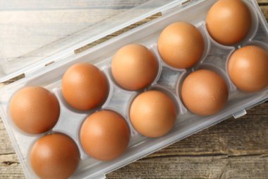 Ahşap masadaki kabın içinde çiğ tavuk yumurtası, yakın plan.