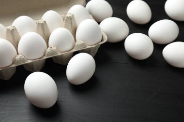 Siyah ahşap masada çiğ tavuk yumurtası, yakın plan.