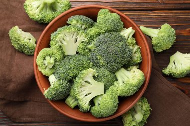 Fresh raw broccoli in bowl on table, flat lay