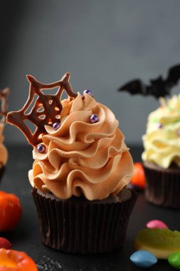 Çikolata ağlı lezzetli kek ve koyu dokulu masa üzerinde gri arka planda renkli şekerler, yakın plan. Cadılar Bayramı