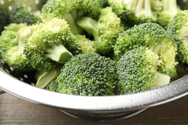 Fresh raw broccoli in colander on table, closeup
