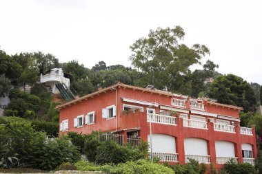 Kırmızı bina ve tepelerdeki birçok farklı bitki.