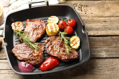 Izgara biftekli tava, biberiye ve sebzeler ahşap masada, yakın plan. Metin için boşluk