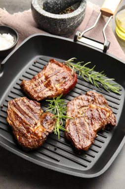 Izgara biftekli tava, biberiye ve baharatlar gri masada, yakın plan.