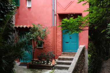 Beautiful red building with green door and different plants outdoors