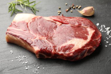 Bir parça çiğ et ve baharat siyah masada, yakın plan.