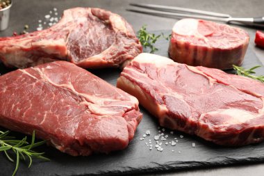 Çiğ et, baharat ve çatal parçaları gri masada, yakın plan.