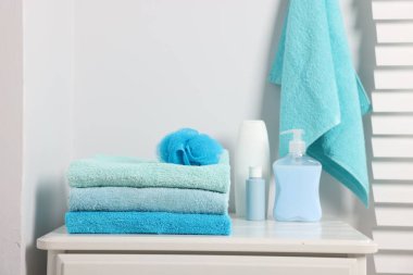 Temiz havlu, sünger ve kozmetik ürünleri banyodaki beyaz şifoniyere yığılmış.