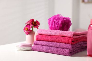 Temiz havlular, çiçekler, sünger ve kozmetik ürünleri beyaz masa içinde, yakın plan.