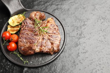 Biberiyeli ızgara biftek, kabak ve domatesli koyu dokuma masa. Metin için boşluk