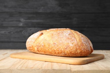 Hafif ahşap masada bir somun taze ekmek, yakın plan.