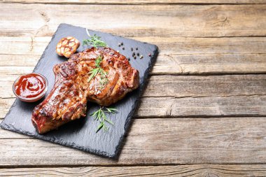 Ahşap masa üzerinde baharat ve ketçaplı lezzetli ızgara biftek. Metin için boşluk