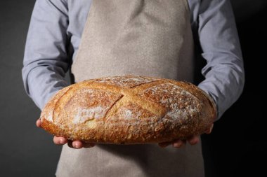 Siyah arka planda taze ekmeği olan fırıncı, yakın plan.