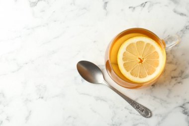 Aromatik çay, fincanda limon ve beyaz mermer masada kaşık, üst manzara. Metin için boşluk
