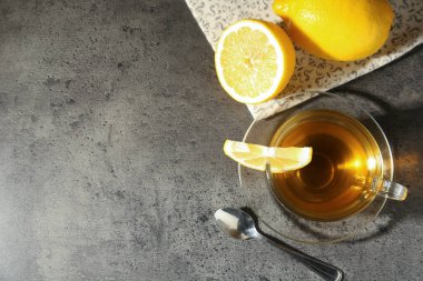 Limonlu ve kaşıklı fincanda romatik çay gri masada, düz yerde. Metin için boşluk