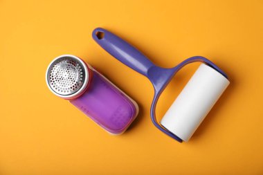 Lint roller and fabric shaver on orange background, flat lay