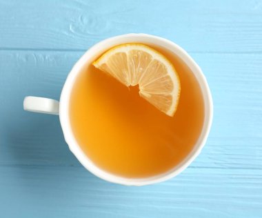 Açık mavi ahşap masada limonlu Aromatik çay, üst manzara.