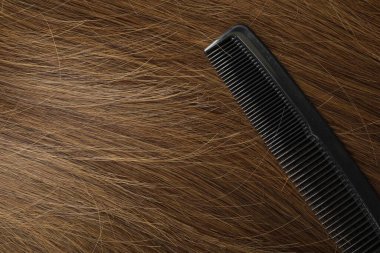 Comb with beautiful brown hair, closeup view