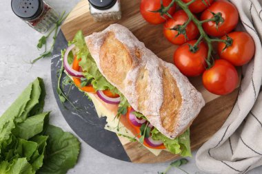 Nefis ciabatta sandviçi jambonlu, peynirli ve sebzeli açık gri masada, düz yatıyordu.