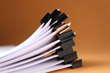 Many documents with binder clips on brown background, closeup