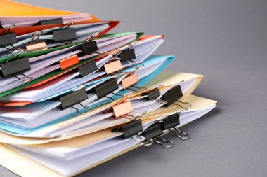 Many folders with documents and binder clips on grey background, closeup