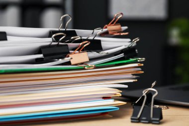 Ahşap masanın üzerinde doküman ve dizüstü bilgisayarı olan birçok dosya, yakın plan