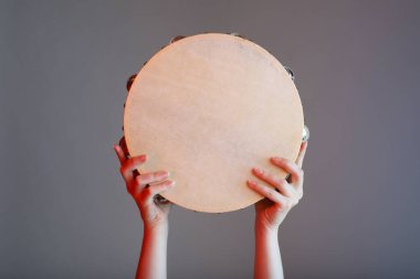 Gri arka planda tef çalan kadın, yakın plan.