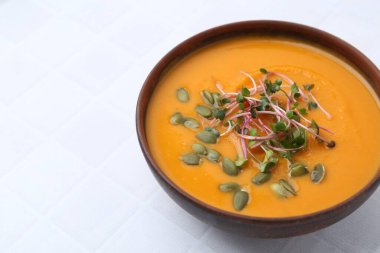 Çekirdekli balkabağı çorbası ve beyaz fayanslı masada mikro yeşillikler, yakın plan. Metin için boşluk