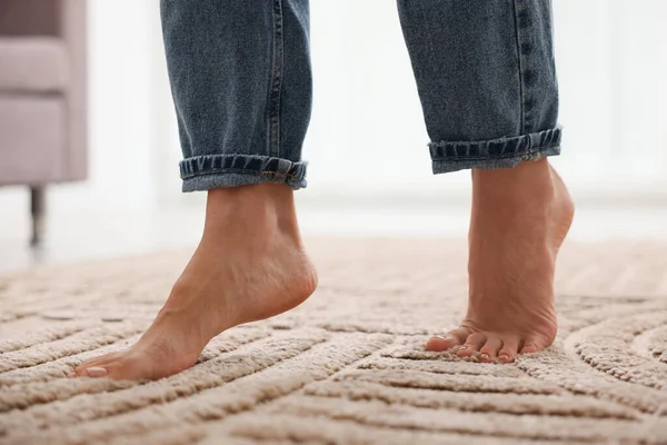 Evdeki yumuşak bej halıda yalınayak yürüyen kadın, yakın plan.