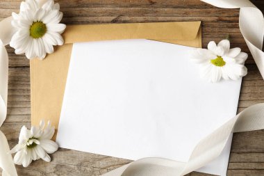 Boş kart, zarf, çiçekler ve kurdele ahşap masa, düz uzanma