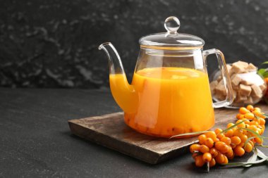 Çaydanlıkta deniz dikenli çay, taze böğürtlen ve siyah masada kahverengi şeker, yakın plan. Metin için boşluk