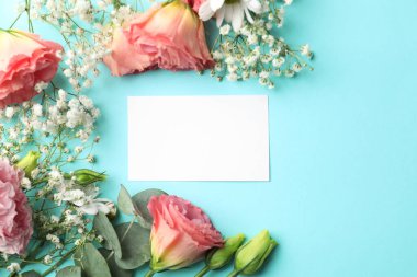 Açık mavi arka planda boş kart ve çiçek dekoru, düz yatış. Metin için boşluk